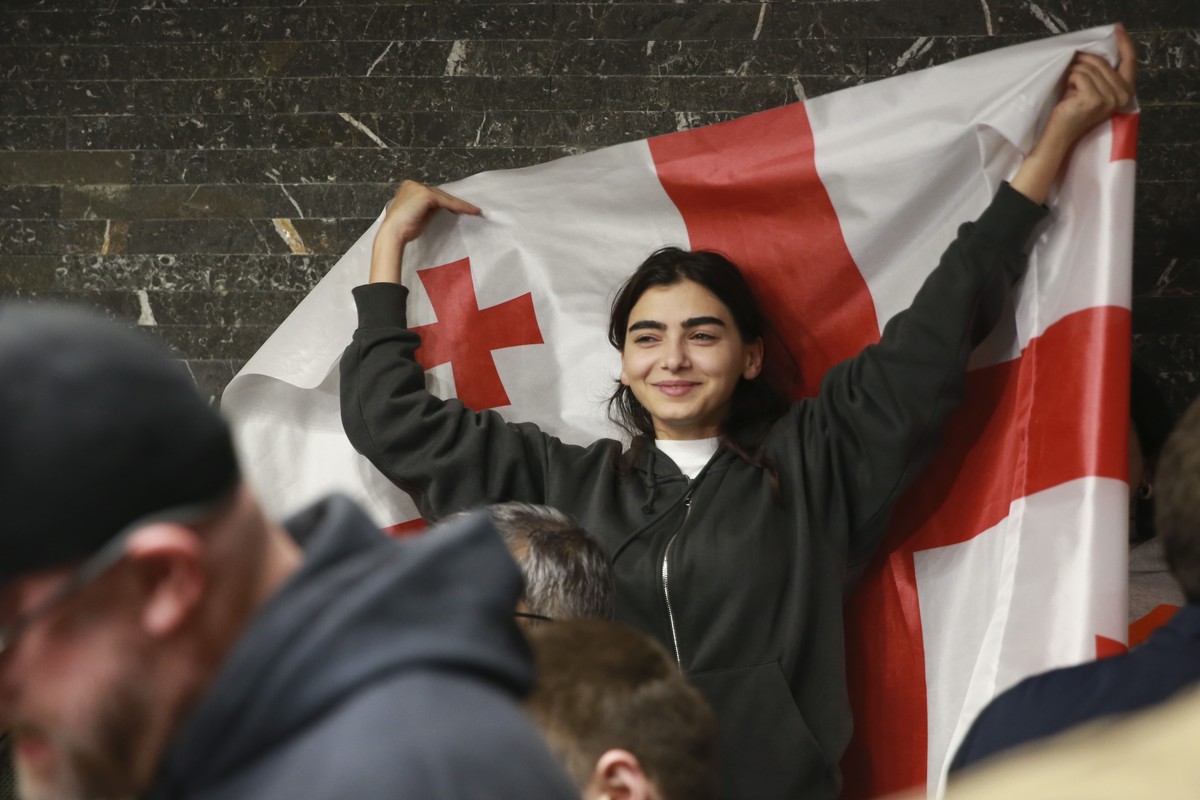 A supporter of the Coalition for Change holds a Georgian flag at coalition's headquarters after polls closing at the parliamentary election in Tbilisi, Georgia, Saturday, Oct. 26, 2024. (AP Photo ...