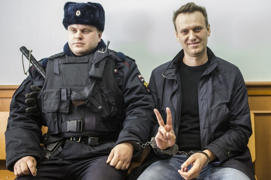 FILE - In this file photo taken on Thursday, March 30, 2017, Russian opposition leader Alexei Navalny, right, shows a V-sign for the media in court in Moscow, Russia. As Russia's most determined ...
