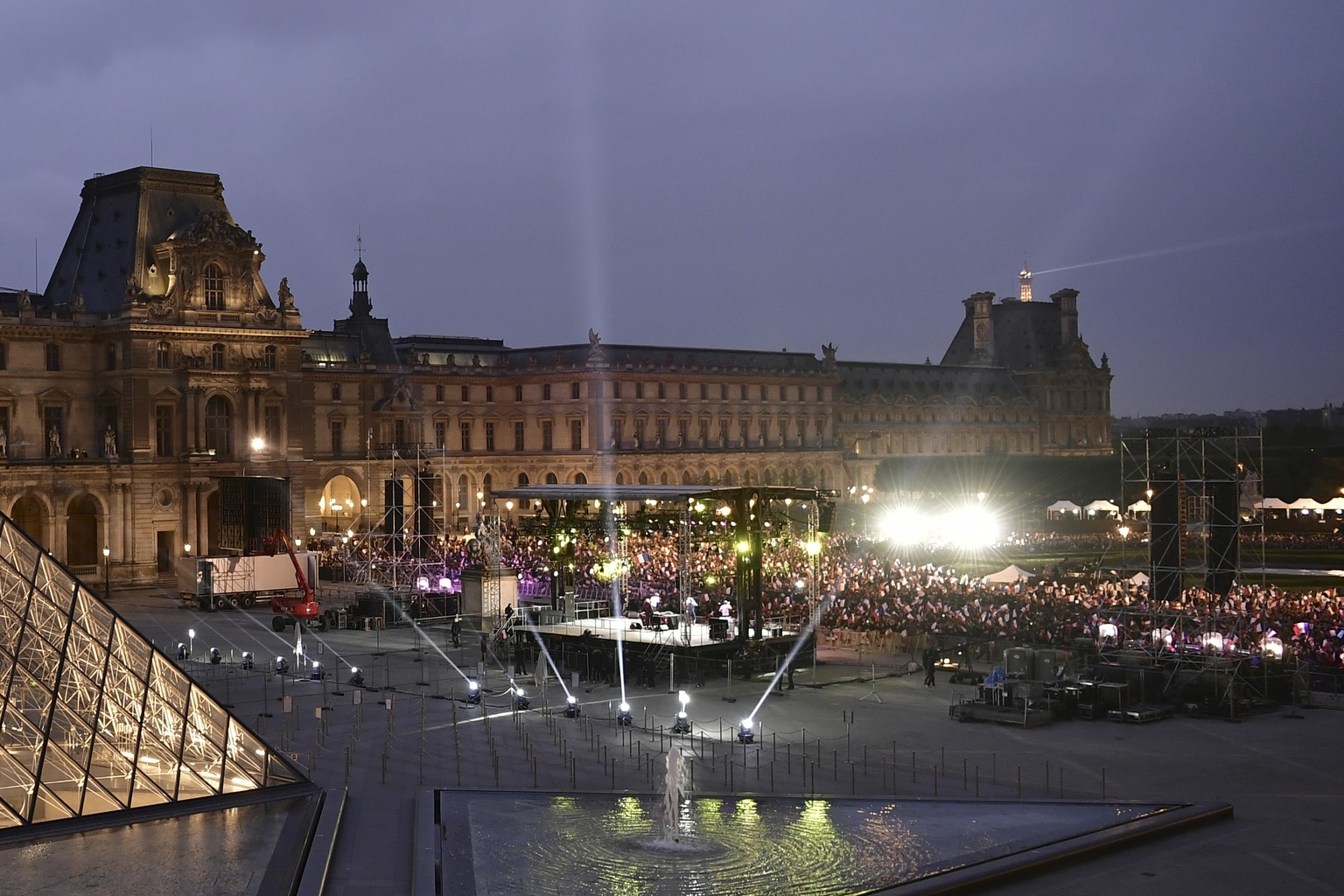 Supporters of incoming French President Emmanuel Macron wait in front of a stage, rear right, for Macron to address them at the Louvre Palace in Paris, Sunday May 7, 2017. Polling agencies have projec ...