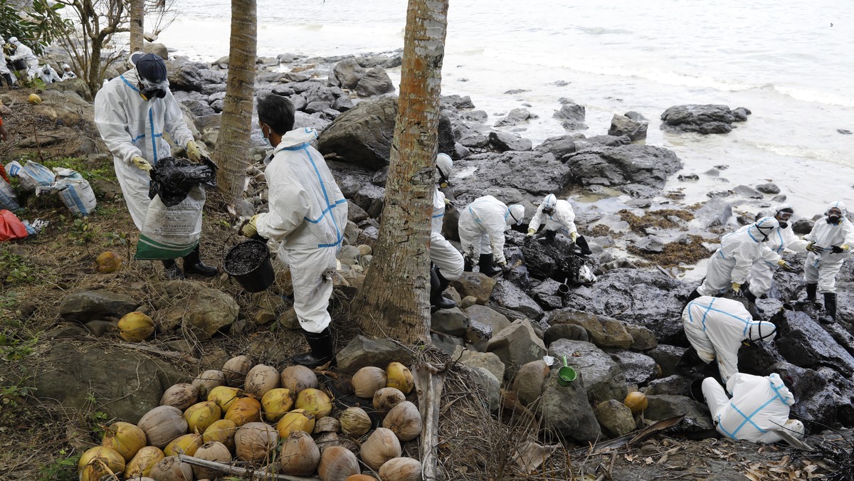 epa10505822 Filipino fishermen wearing protective suits collect oily waste along a beach in the coastal town of Pola, Mindoro island, Philippines, 06 March 2023. Affected fisherfolk were tapped by the ...