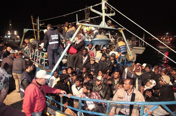 epa02721649 Italian coastguards look on as Libyan refugees arrive on the tiny island of Lampedusa, Italy in the early hours of 07 May 2011. Coast guard officials said two vessels with 842 people on bo ...