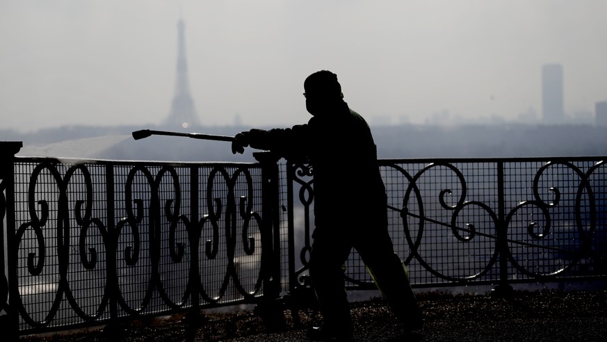 A worker wearing protective gears sprays disinfectant as a precautionary measure against COVID-19 during a nationwide confinement to counter the virus, in Suresnes, outside Paris, Tuesday, March 31, 2 ...