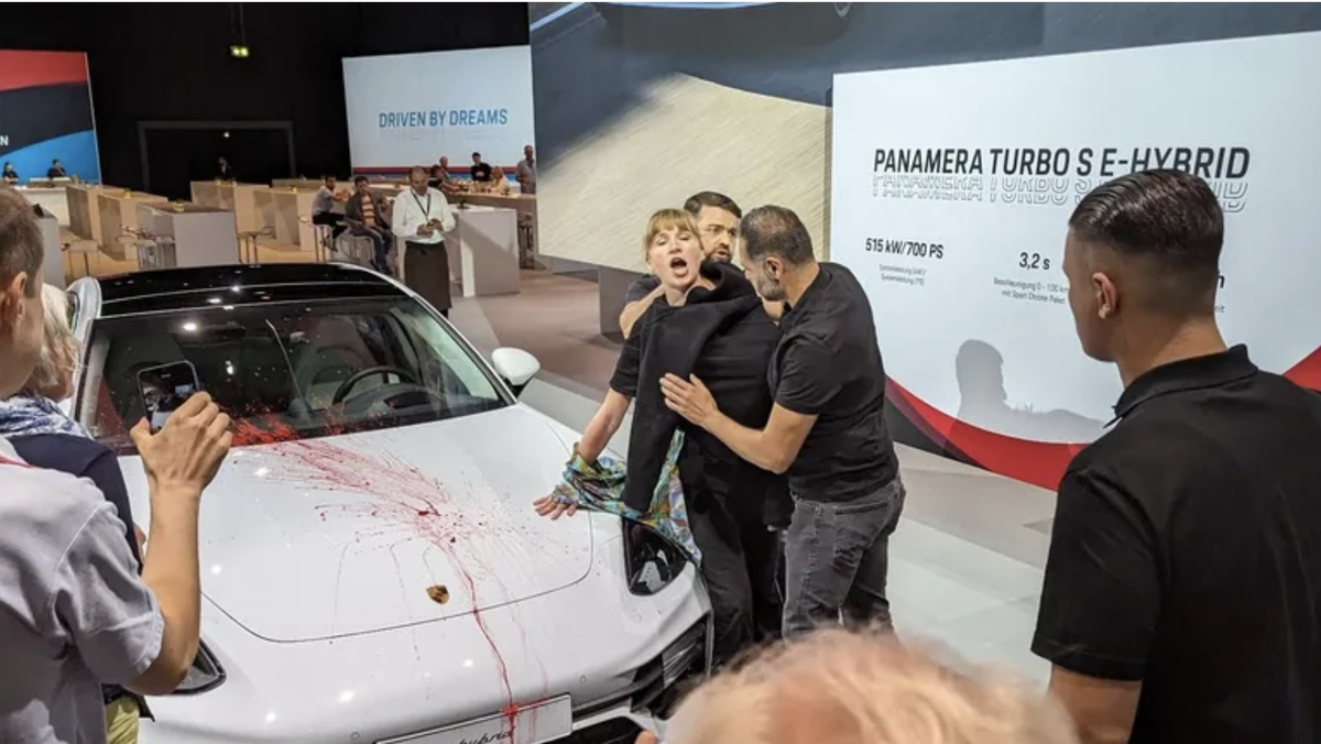 Protest in der Stuttgarter Porsche Arena: Eine Aktivistin hat sich bei entblößten Brüsten an einen Porsche geklebt. Zuvor beschmierte sie das ausgestellte Fahrzeug.