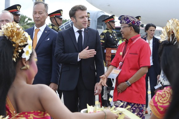 epa10305034 French President Emmanuel Macron (center) speaks to Balinese ruler Wayan Coster (right) upon arrival at Ngurah Rai International Airport ahead of the G20 summit in Bali, Indonesia, November 14 2 ...