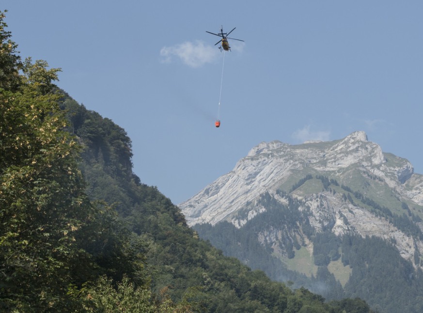 Ein Helikopter transportiert Löschwasser zum Absturzort am Lopper in Hergiswil NW. (Archivbild)