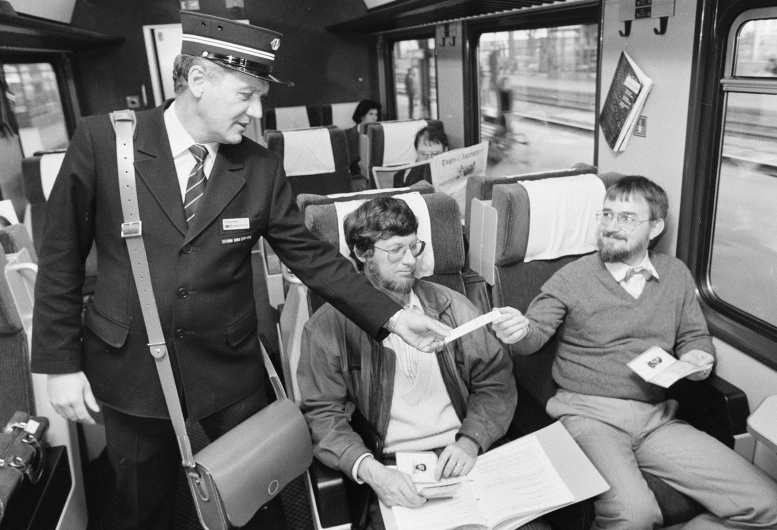 Ein Kondukteur der SBB kontrolliert die Fahrscheine von zwei Zugpassagieren in der 1. Klasse, aufgenommen 1992. (KEYSTONE/Str)