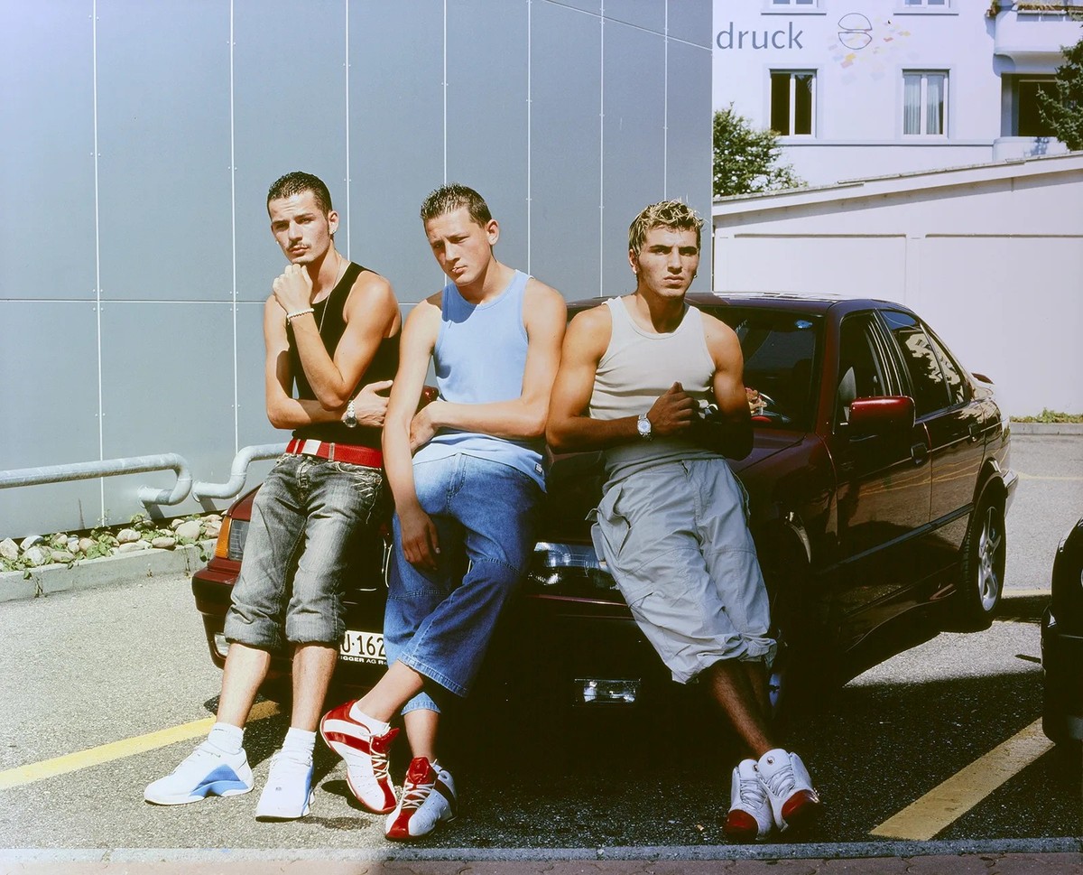 In der Jugendkultur wird der postjugoslawische Einfluss besonders sichtbar. Junge Männer mit kosovo-albanischem Hintergrund posieren vor einem BMW. Fotografie von Paco Carascosa, 2004.
https://permali ...