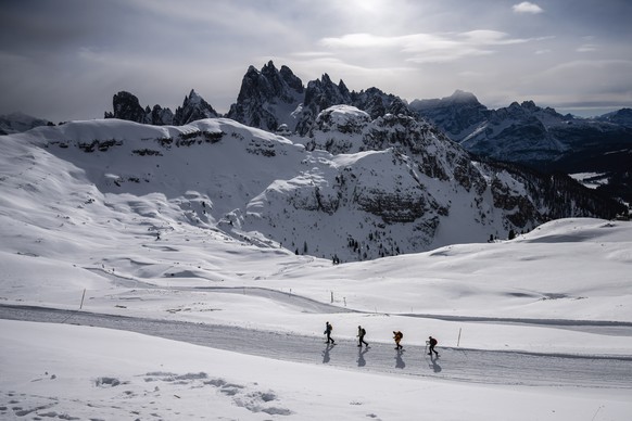 epaselect epa10434523 People go snowshoe hiking on a snow covered path at the foot of the Tre Cime di Lavaredo (Three Peaks of Lavaredo) of the Dolomites mountains on a sunny winter day, near Auronzo  ...
