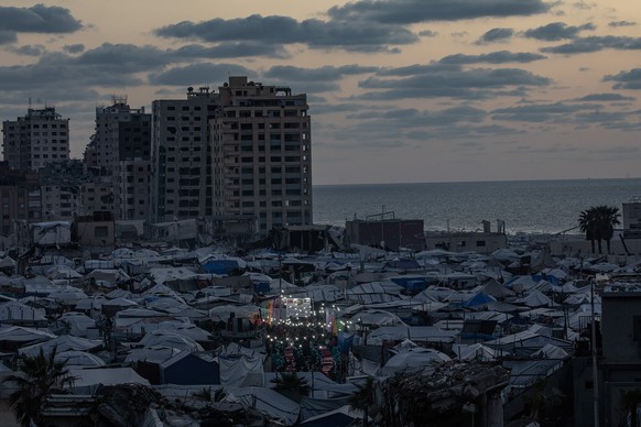 epa12799635 Displaced Palestinian people gather between makeshift tents to break their fast with an iftar meal together during the holy fasting month of Ramadan in the west of Gaza, 06 March 2026. Mus ...