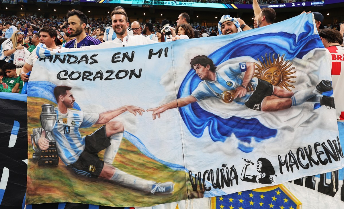 epa10331316 Fans of Argentina hold a banner depicting Lionel Messi (L) and Diego Maradona (R) in the manner of Michelangelo's painting 'The Creation of Adam' during the FIFA World Cup 2 ...