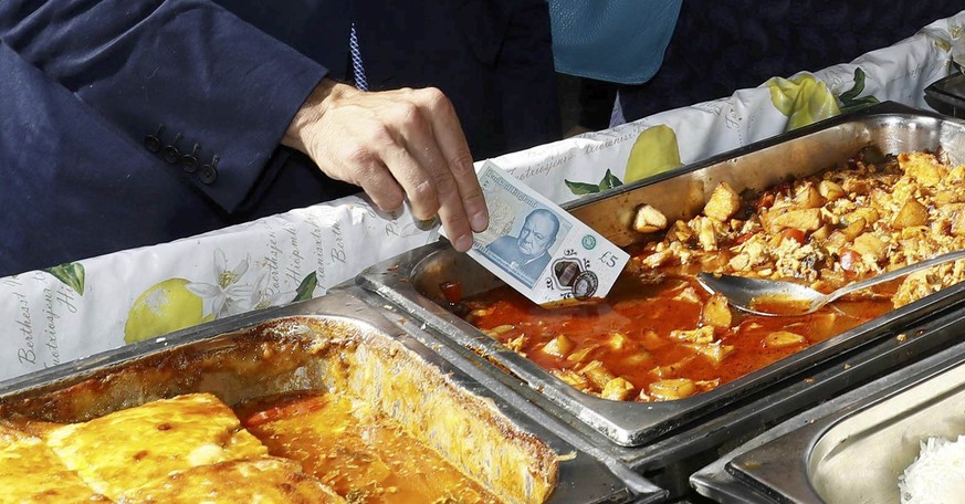 Bank of England governor Mark Carney tests a new polymer five pound note as he buys lunch at Whitecross Street Market in London, Britain September 13, 2016. REUTERS/Stefan Wermuth/File Photo