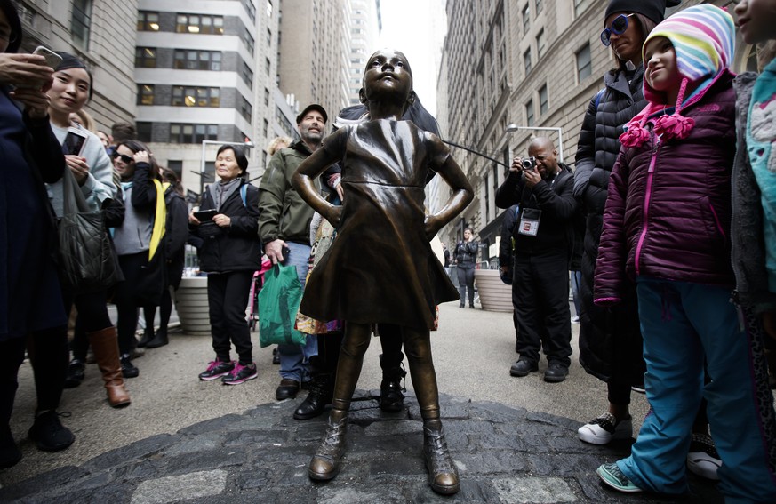 epa05874215 People look at the &#039;Fearless Girl&#039; girl statue in Lower Manhattan following a press conference with New York City Mayor Bill de Blasio (unseen) where he announced that the city h ...