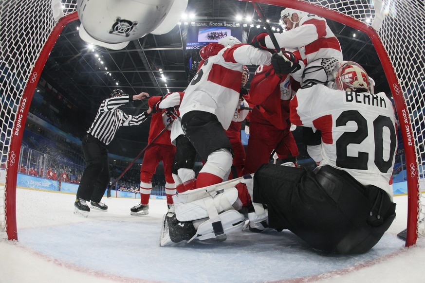 Switzerland&#039;s goalkeeper Reto Berra (20) is pushed into the net as players fight in front of the goal during a preliminary round men&#039;s hockey game between Switzerland and Russian Olympic Com ...