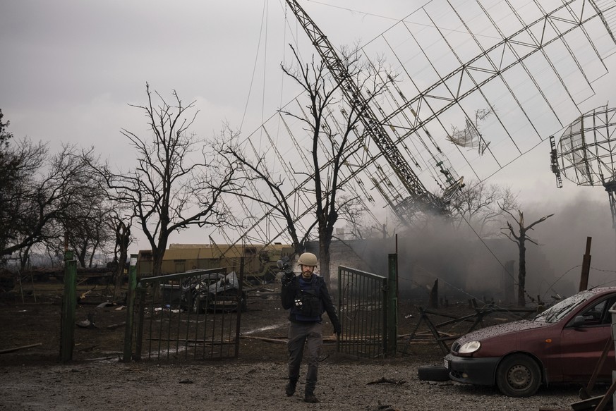 Associated Press videographer Mstyslav Chernov walks amid smoke rising from an air defense base in the aftermath of a Russian strike in Mariupol, Ukraine, Thursday, Feb. 24, 2022. (AP Photo/Evgeniy Ma ...