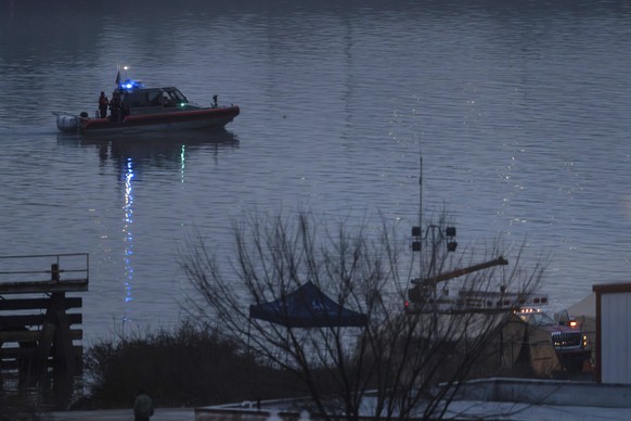 A boat continues to patrol as night falls offshore from emergency vehicles and recovery operations near the mouth of the Anacostia River at the Potomac River near Ronald Reagan Washington National Air ...