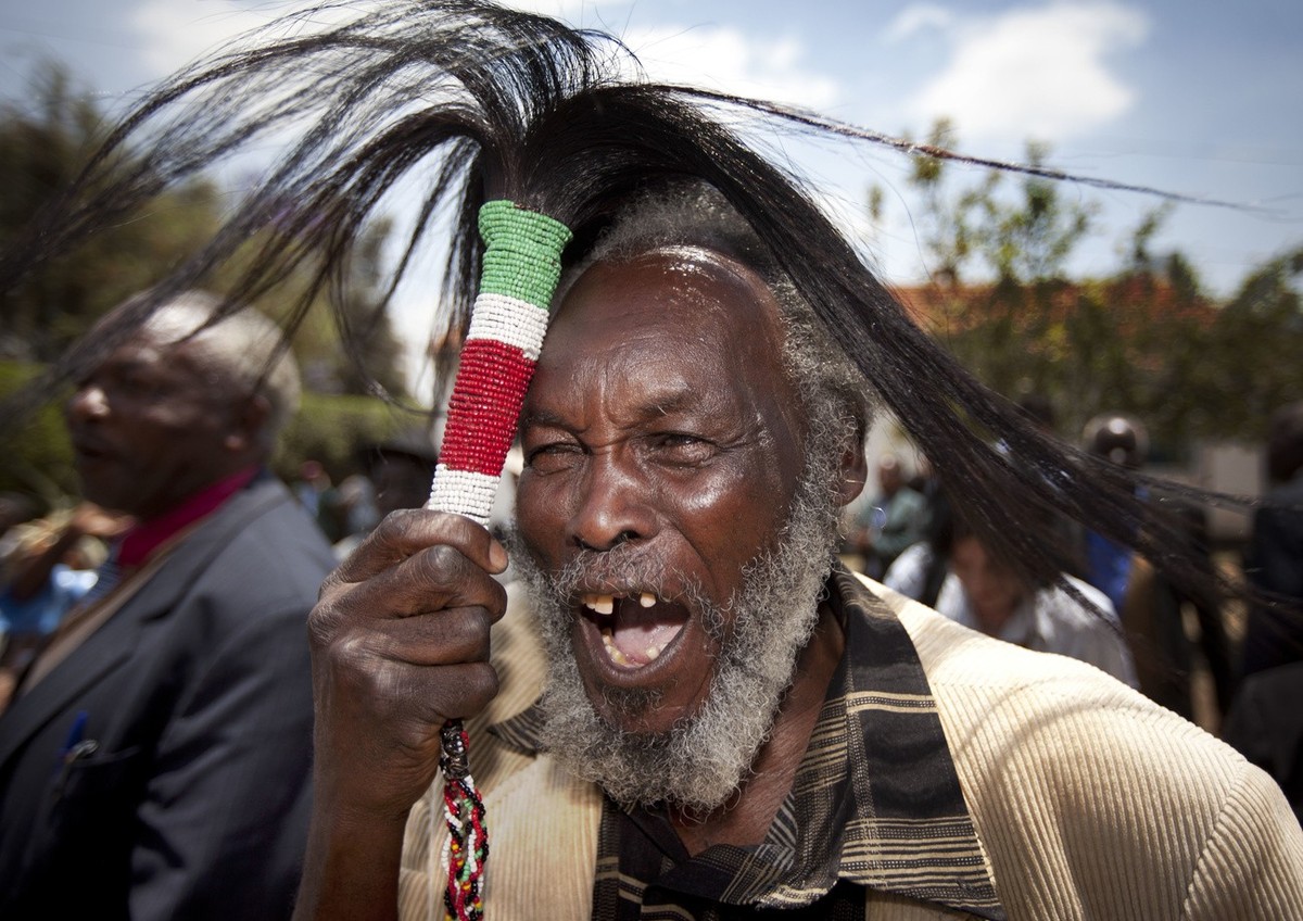 Lawrence Mathenge, representative of the Mau Mau War Veterans Association, celebrates the announcement of a legal decision in Britain's High Court concerning Mau Mau veterans, while holding a cer ...