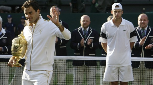 Roger Federer of Switzerland (L) waves as he holds his trophy after defeating Andy Roddick of the U.S. (R) in their Gentlemen&#039;s Singles finals match at the Wimbledon tennis championships in Londo ...