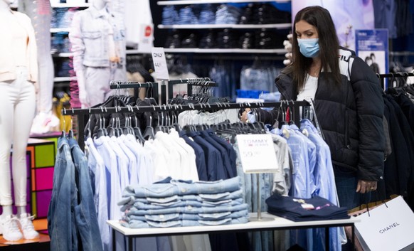 A woman wearing protective face mask chooses clothes in the Swiss department store Manor the day of its reopening during the state of emergency of the coronavirus disease (COVID-19) outbreak, in Lausa ...
