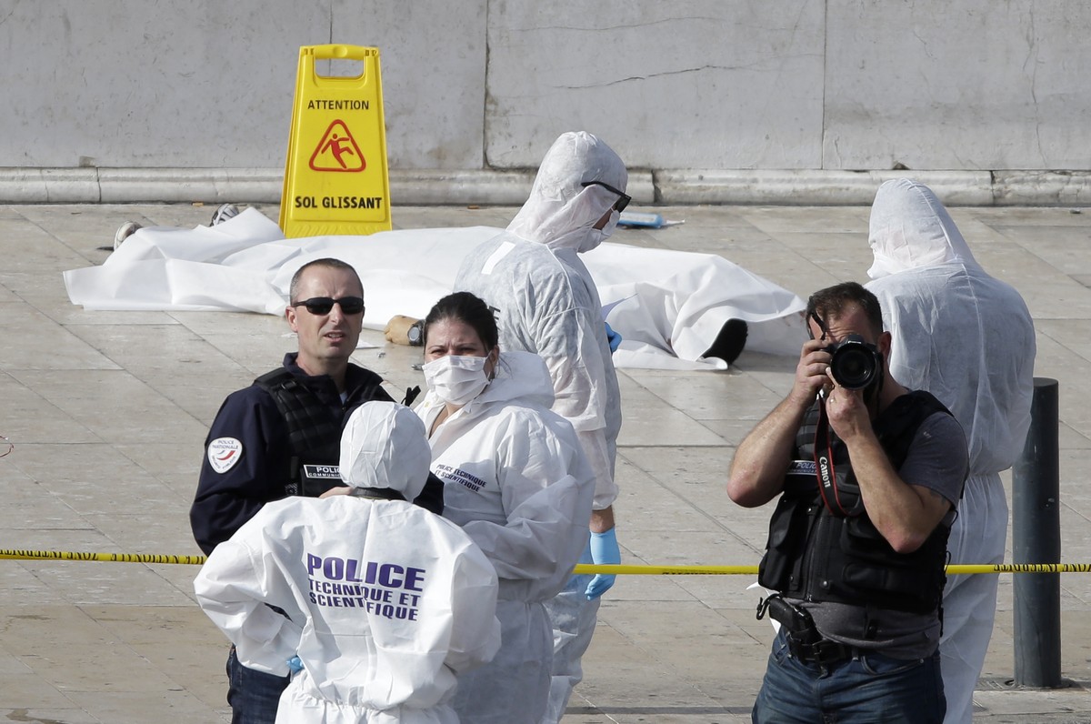 Investigative police officer work by a body under a white sheet outside Marseille 's main train station Sunday, Oct. 1, 2017 in Marseille, southern France. A man with a knife attacked people at t ...