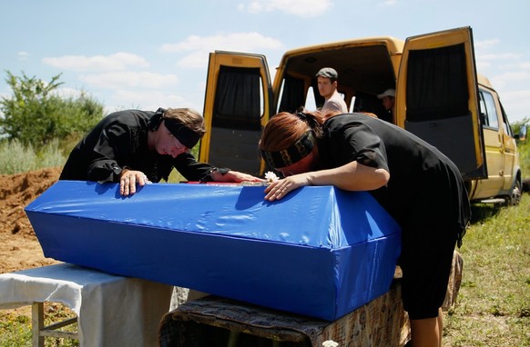 epa05411437 Relatives cry on coffins of dead children during the funeral ceremony in the Yenakiieve of Donetsk area, Ukraine, 06 July 2016. The three children (11, 5 and 1.5 years old) were killed in  ...