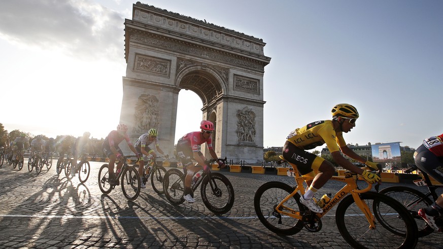 epaselect epa07746324 Colombia's Egan Bernal (R) of Team Ineos wears the overall leader's yellow jersey as he passes with the pack by the Arc de Triomphe during the 21st and final stage of the 106th e ...