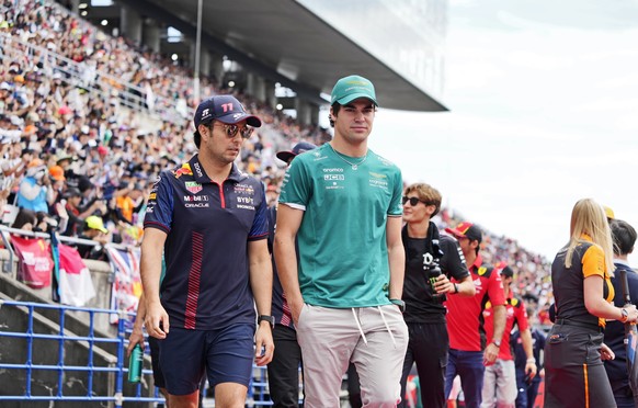 epa10879751 Mexican Formula One driver Sergio Perez (L) of Red Bull Racing and Canadian Formula One driver Lance Stroll (C) of Aston Martin walk together during the drivers parade ahead of the Formula ...