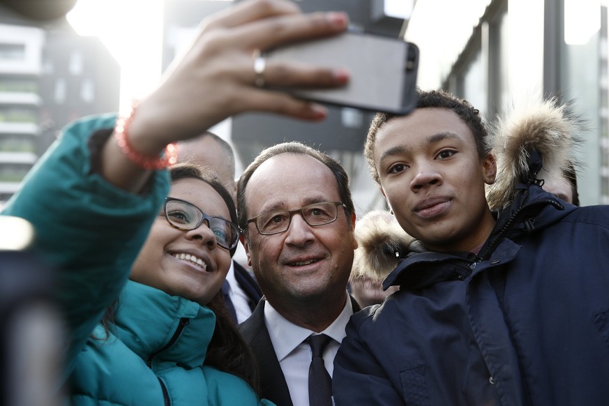 epa05799322 French President Francois Hollande (C) poses for selfies with locals during a visit to the Zac du Plateau neighborhood in the Ivry Sur Seine, south of Paris, France, 17 February 2017. The  ...