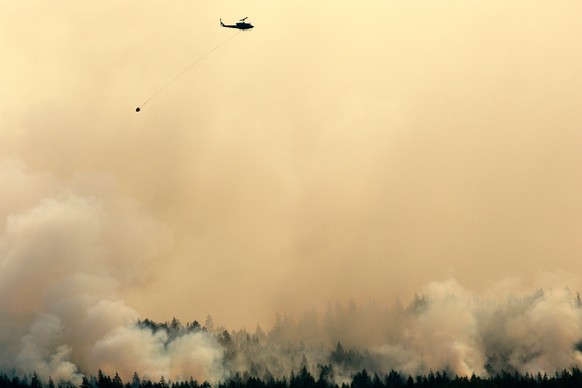 A helicopter flies by the Wesley Ridge wildfire near Cameron Lake where an out-of-control fire continues to burn near Coombs, British Columbia, Sunday, Aug. 3, 2025. (Chad Hipolito/The Canadian Press  ...