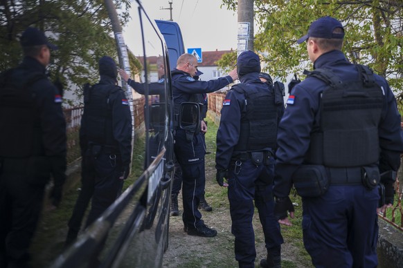 Police officers prepare for a chase in the village of Dubona, some 50 kilometers (30 miles) south of Belgrade, Serbia, Friday, May 5, 2023, near the site of an attack on Thursday night.  A gunman killed...