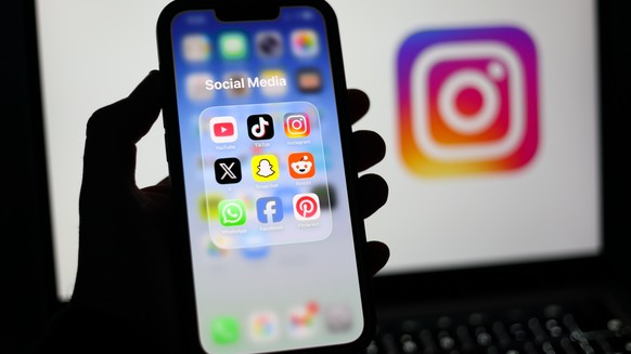 epa12674741 Social media applications displayed on a mobile phone alongside the Instagram logo displayed on a laptop screen in Liverpool, Britain, 23 January 2026. A proposal to ban under-16s from acc ...
