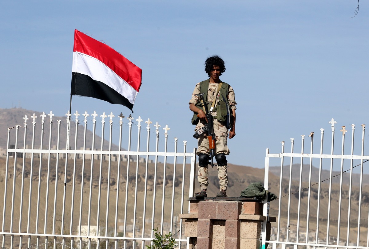 epa07464816 A Houthi militiaman stands guard near a Yemeni flag during a rally commemorating the fourth anniversary of the Saudi-led military campaign on Yemen, in Sana'a, Yemen, 26 March 2019. A ...