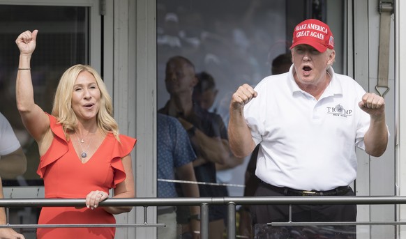 epa10100934 Republican Congresswoman Majorie Taylor Greene of Georgia (L) and former US President Donald J. Trump (R) cheer with fans while watching the third round of the LIV Golf Bedminster invitati ...