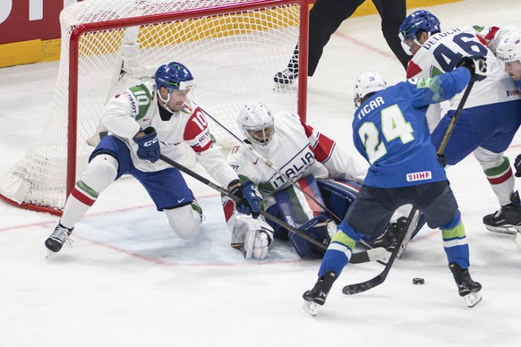 Italy's Peter Spornberger, left, and Italy's goaltender Damian Clara, center, vies for the puck against Slovenia's Rok Ticar during the 2026 IIHF Men's Ice Hockey World Championshi ...