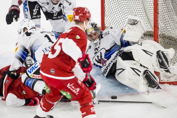 Le gardien Fribourgeois Reto Berra, droite, contre les tirs des joueurs lausannois lors de la rencontre du championnat suisse de hockey sur glace de National League entre le Lausanne Hockey Club, LHC, ...