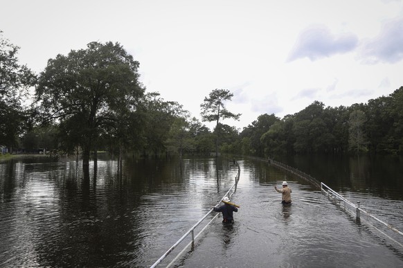 Mike Davis, left, and Trent Tipton, both line workers from Woodville, Texas, walk through floodwater to try to restore power for a customer on Friday, Sept. 20, 2019, in the Mauriceville, Texas, area. ...