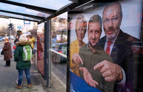 A billboard showing an AI-generated image of Ukrainian President Volodymyr Zelenskyy, center, flanked by European officials is displayed at a bus stop in Budapest, Hungary, Monday, Feb. 23, 2026. (AP  ...