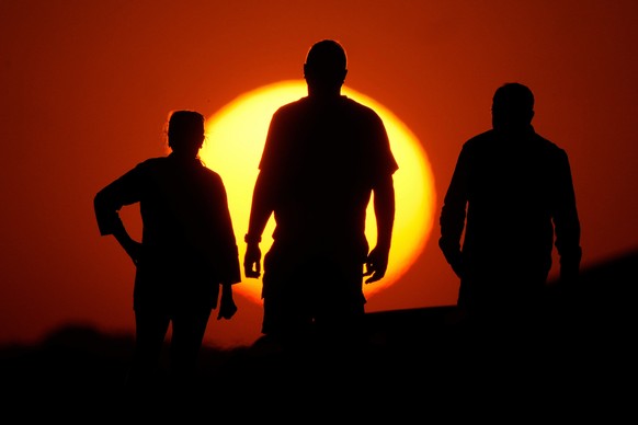 FILE - People watch the sunset from the Liberty Memorial grounds in Kansas City, Mo., May 12, 2025. (AP Photo/Charlie Riedel, File)
Climate Change Economic Impact