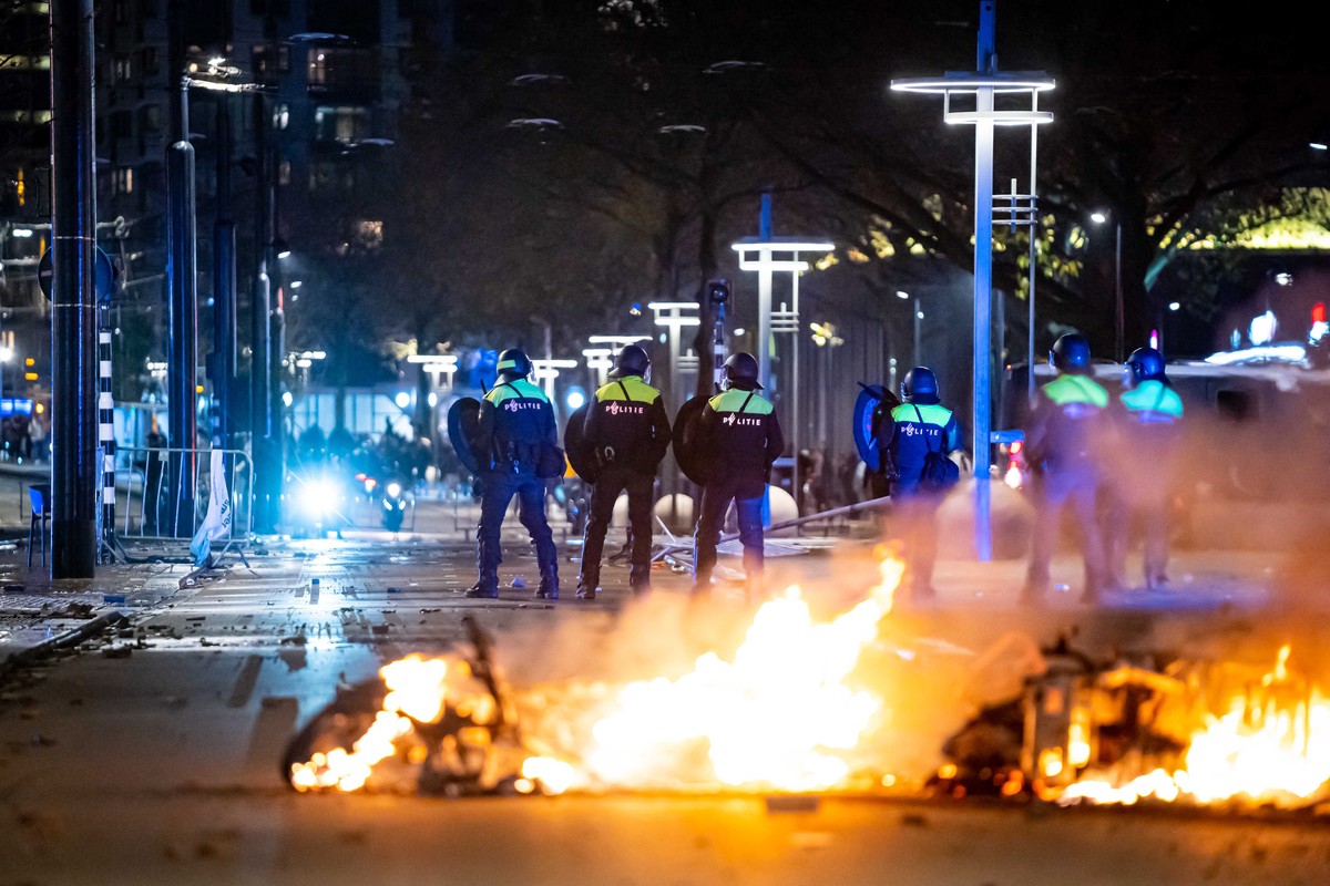 epaselect epa09593019 Policemen stand near burning objects after a protest against the '2G policy' turned into riots, with protesters setting fires in the street and destroying police cars a ...