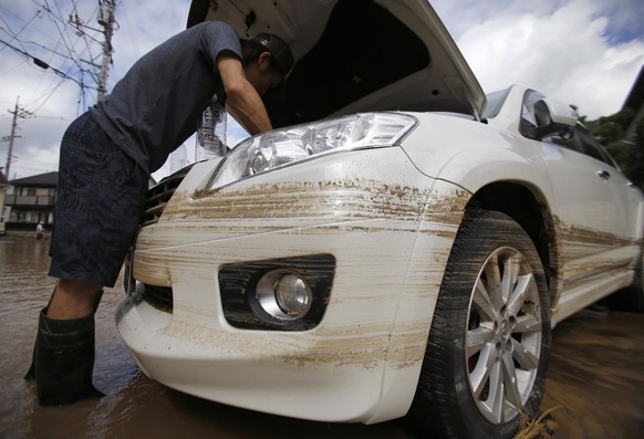 A local resident looks at his Toyota SUV, which was damaged by a flood at a site where a landslide swept through a residential area at Asaminami ward in Hiroshima, western Japan, August 21, 2014. At l ...