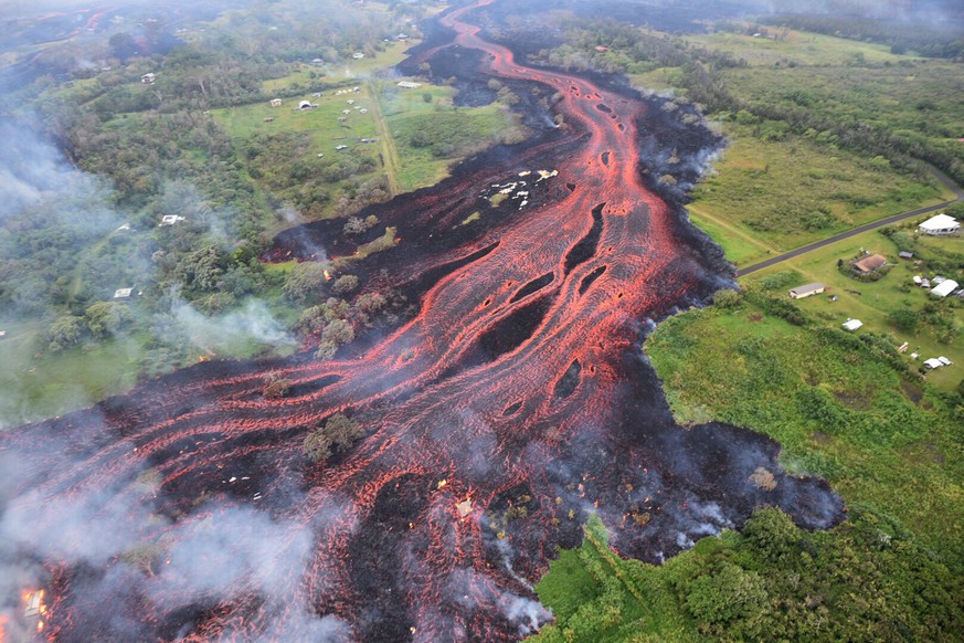 FILE - In this May 19, 2018 aerial file photo released by the U.S. Geological Survey, lava flows from fissures near Pahoa, Hawaii. White plumes of acid and extremely fine shards of glass billowed into ...