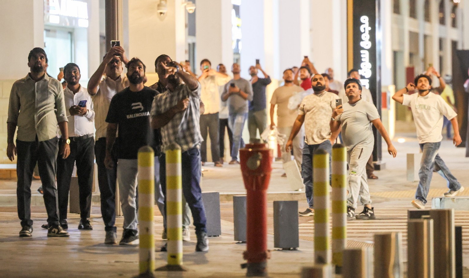 epa12785120 People look and record with their phones missiles and smoke on the night sky over Doha, Qatar, 28 February 2026. Qatar announced a successful defence against rocket attacks on its state te ...