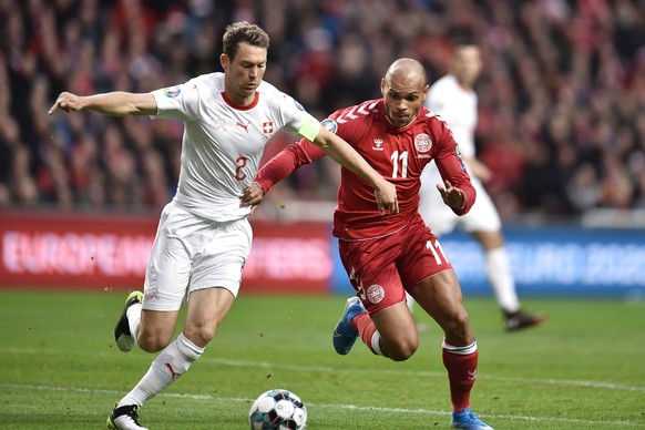 Switzerland&#039;s Stephan Lichtsteiner, left, and Denmarks Martin Braithwaite challenge for the ball during the Euro 2020, Group qualifying soccer match between Denmark and Switzerland in Telia Parke ...