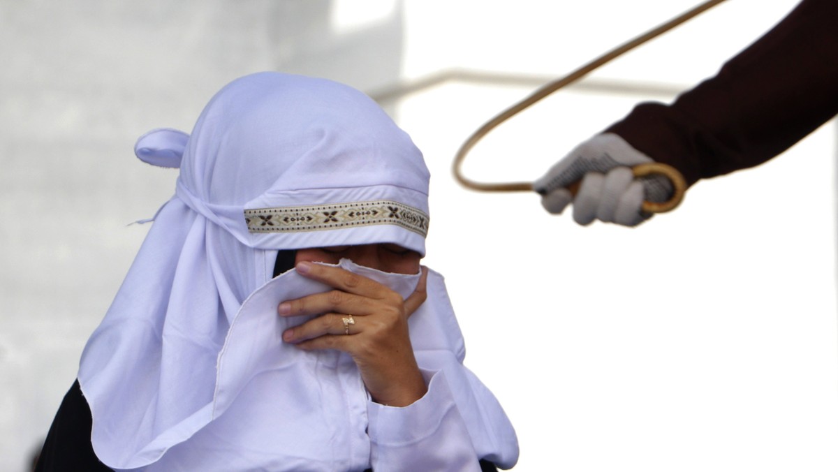 epa06680855 An Acehnese woman covers her face as she is caned in public for violating sharia law in Banda Aceh, Indonesia, 20 April 2018. Aceh's provincial government has decided to end the canin ...
