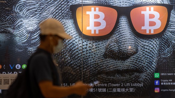 epaselect epa09486742 A man walks past an advertising poster for Bitcoins and cryptocurrencies in Hong Kong, China, 25 September 2021. On 24 September, China intensified the crackdown on cryptocurrenc ...