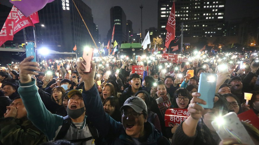 epa05638081 South Koreans hold up their smartphones with light as they march toward presidential house and banner reading &#039;Park Geun-Hye Out&#039; during a rally against South Korean President Pa ...