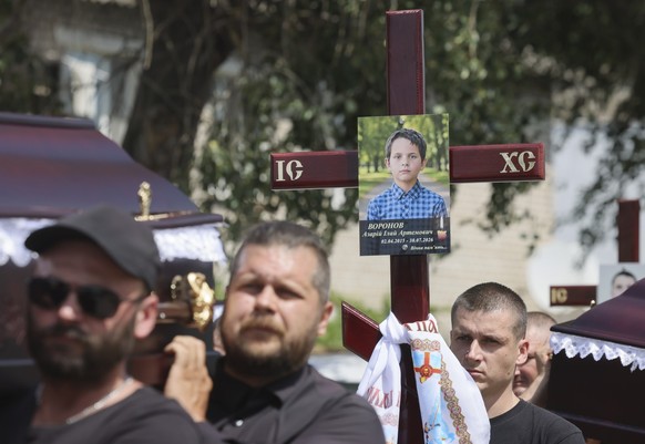 epa13148425 Mourners carry the coffins during the funeral of Voronov family members who were killed in a Russian ballistic missile strike on their home in the village of Radushne, on the outskirts of  ...