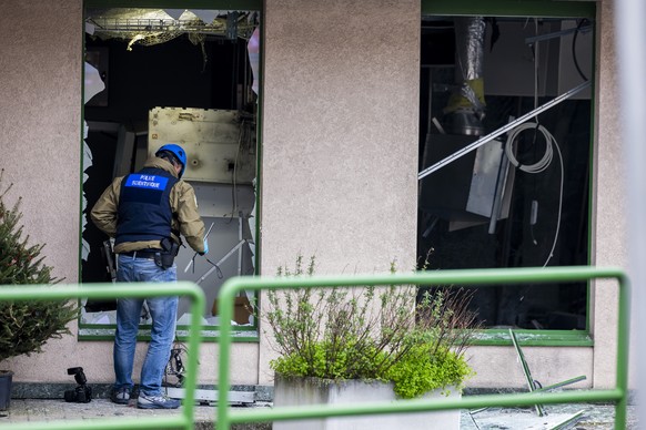 KEYPIX - Un inspecteur de la police scientifique examine une vitrine de la banque UBS apres l'attaque a l'explosif du distributeur automatique de billets, survenue dans la nuit, ce mercredi  ...