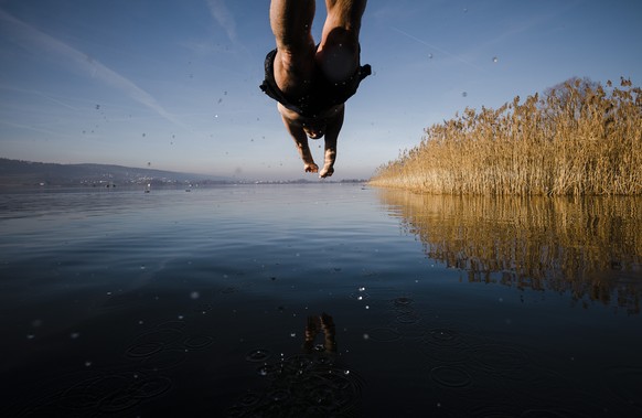 A man jumps into the lake Greifensee on a sunny New Year&#039;s Day morning in the village of Greifensee near Zurich, Switzerland on Saturday, January 1, 2022. (KEYSTONE/Michael Buholzer)