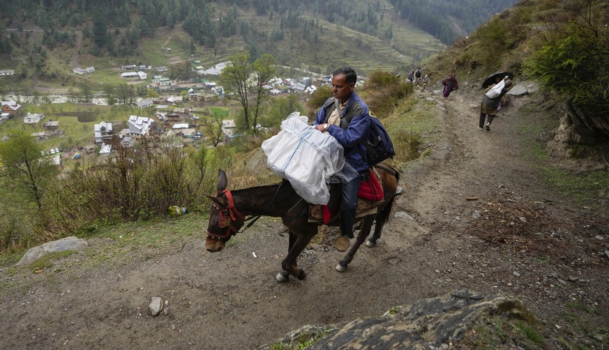 An election official sits on a horse back holding an electronic voting machine as he heads to a polling booth in a remote mountain area on the eve of the first round of voting in the six-week long nat ...