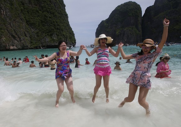 Tourists jump in the waves on Maya Bay, Phi Phi Leh island in Krabi province, Thailand, Thursday, May 31, 2018. The popular tourist destination of Maya Bay in the Andaman Sea will close to tourists fo ...